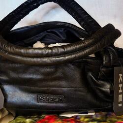 Schwarze Tasche mit rundem Henkel auf Stoffen