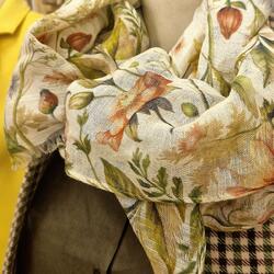 Nahaufnahme eines hellen Schals mit Blumenmuster über olivgrüner Jacke