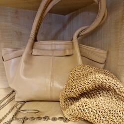 Beige Tasche mit Schmuck und geflochtenem Hut im Regal